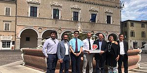 Matteo Ricci insieme alla delegazione cinese in piazza del Popolo con in mano il logo "We Pesaro"