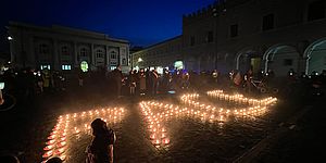 Scritta "PACE" formata da candele sul paviemento della piazza