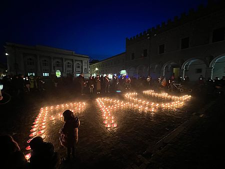Scritta "PACE" formata da candele sul paviemento della piazza