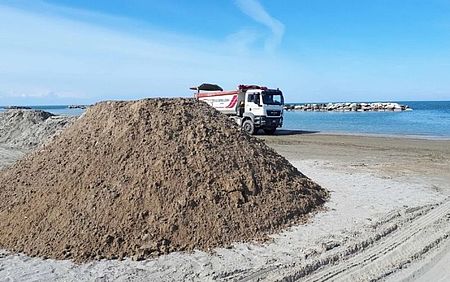 Camion con montagna di sabbia in spiaggia